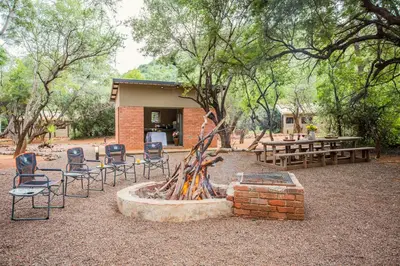a group of chairs and a fire pit in front of a building at Zwartkloof Adventures Tented Camp in Bela-Bela