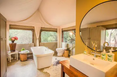 a bathroom with a tub and a sink and a mirror at Zwartkloof Adventures Tented Camp in Bela-Bela