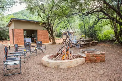 a group of chairs and a fire pit in front of a building at Zwartkloof Adventures Tented Camp in Bela-Bela