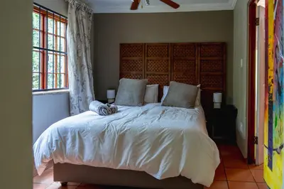 a bedroom with a large bed with white sheets at GILLFORD GALLERY ACCOMMODATION in Benoni