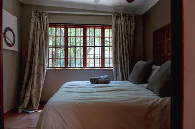 a bedroom with a large bed in front of a window at GILLFORD GALLERY ACCOMMODATION in Benoni