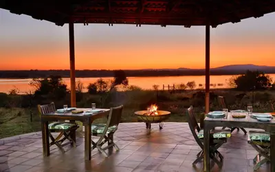 a patio with tables and chairs and a fire pit at Kameeldrift Waterfront Estate & Resort in Brits