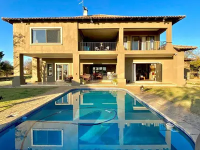 a villa with a swimming pool in front of a house at Kameeldrift Waterfront Estate & Resort in Brits