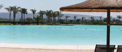 a large swimming pool with a straw umbrella and chairs at Insaka 1 The Blyde Crystal Lagoon Experience in Pretoria