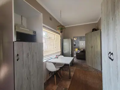 a kitchen with a table and a refrigerator and a room at Ducks Nest in Malelane