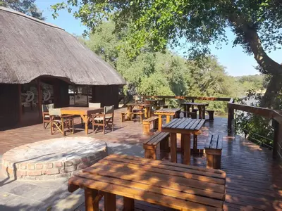 a patio with wooden tables and chairs and a hut at Bushriver Lodge in Mica