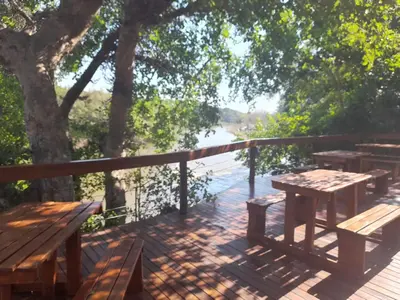 a deck with wooden benches and tables and a tree at Bushriver Lodge in Mica