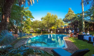 a swimming pool in a park with people sitting around it at Hotel 247 @ White River in White River