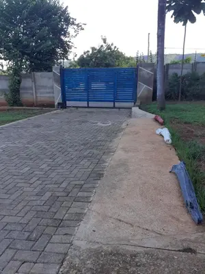 a brick walkway with a blue gate in a park at Thullyteams guesthouse in Tzaneen