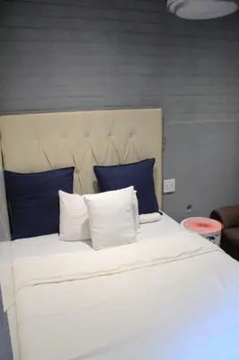 a large white bed with blue pillows in a room at Thullyteams guesthouse in Tzaneen