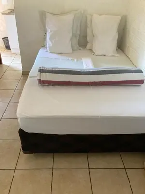 a bed with white sheets and pillows in a room at Thullyteams guesthouse in Tzaneen