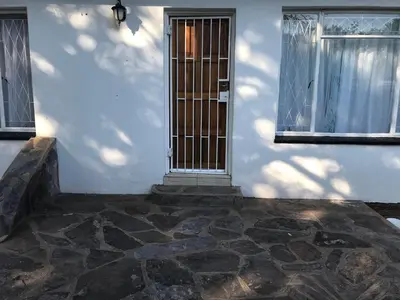 a white building with a door and two windows at The Open Door Guest Suite in Modimolle