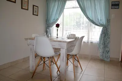 a dining room table with white chairs and a window at The Open Door Guest Suite in Modimolle