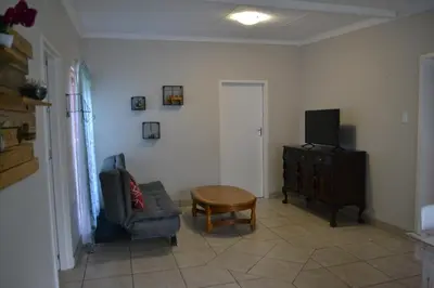 a living room with a couch and a table and a television at The Open Door Guest Suite in Modimolle