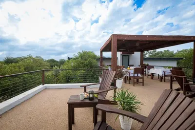 a patio with a table and chairs on a balcony at Gem In The Bush Lodge in Hoedspruit