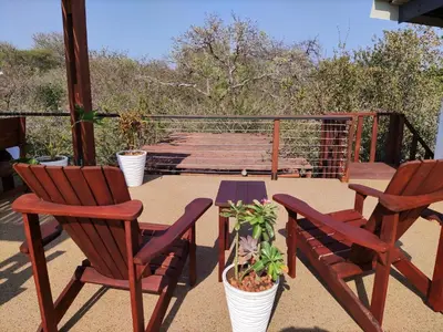 a patio with two chairs and a table with plants at Gem In The Bush Lodge in Hoedspruit