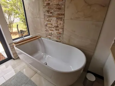 a white bath tub in a bathroom with a window at Gem In The Bush Lodge in Hoedspruit