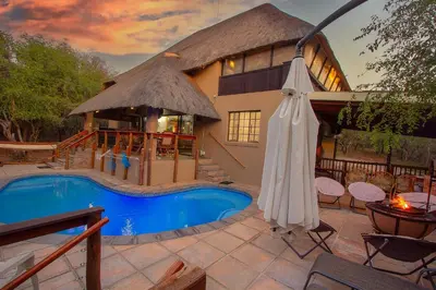 a house with a swimming pool and an umbrella at Khaya Romantica - Bush getaway in Marloth Park