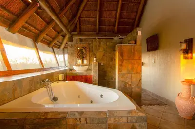a large bath tub in a room with a window at Khaya Romantica - Bush getaway in Marloth Park