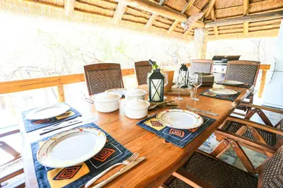 a wooden table with chairs and plates on it at Khaya Romantica - Bush getaway in Marloth Park