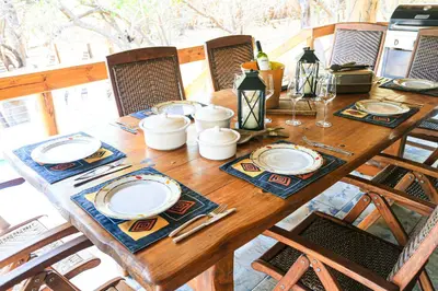 a wooden table with plates and utensils on it at Khaya Romantica - Bush getaway in Marloth Park