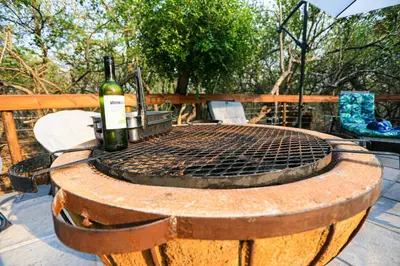 a bottle of wine sitting on top of a grill at Khaya Romantica - Bush getaway in Marloth Park