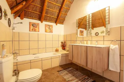 a bathroom with a toilet and a tub and a sink at Khaya Romantica - Bush getaway in Marloth Park