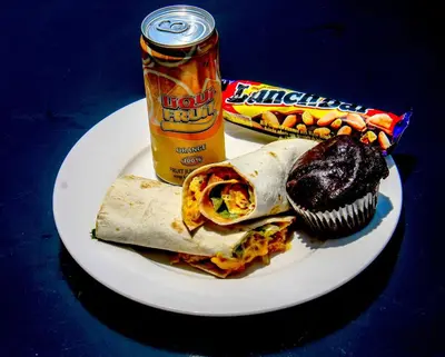 a plate with a burrito and a cupcake and a can of candy at SleepOver Kruger Gate in Skukuza