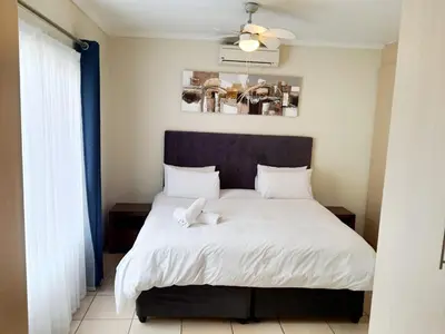 a bedroom with a large white bed with a blue headboard at NST City Apartments @ 9 Joubert in Nelspruit