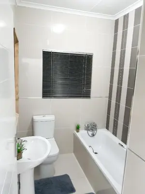 a white bathroom with a tub and a toilet and a sink at NST City Apartments @ Casalinga Villa in Nelspruit