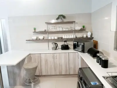 a kitchen with white counters and wooden cabinets at NST City Apartments @ Casalinga Villa in Nelspruit