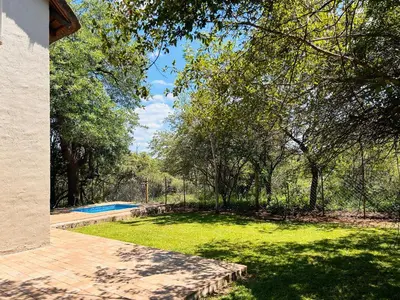 a yard with a swimming pool and trees and grass at Ndoto Cottage in Hoedspruit