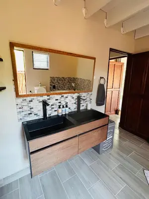 a bathroom with a black sink and a mirror at Ndoto Cottage in Hoedspruit