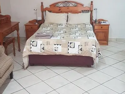 a bedroom with a bed with a wooden headboard at Country Blue Luxury Guest House in Polokwane