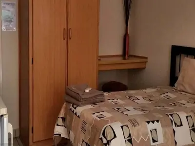 a bedroom with a bed and a wooden cabinet at Country Blue Luxury Guest House in Polokwane