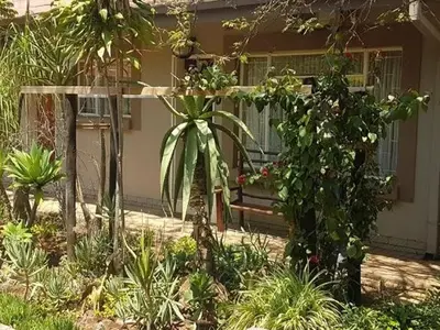 a garden with a bench in front of a house at Country Blue Luxury Guest House in Polokwane