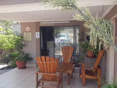 two wooden chairs and a bench on a patio at Country Blue Luxury Guest House in Polokwane