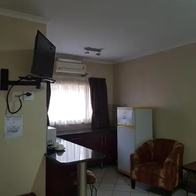 a kitchen with a refrigerator and a table and a chair at Country Blue Luxury Guest House in Polokwane