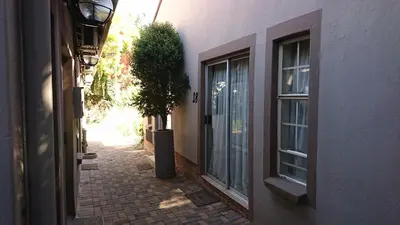 an alley with a building and a tree next to a window at Country Blue Luxury Guest House in Polokwane