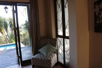 a living room with a chair and a sliding glass door at Patogeng Self Catering - Da Gama Dam view in White River