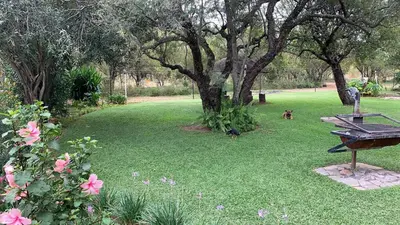 a park with a picnic table and some pink flowers at Farm Vibes Guest House in Brits