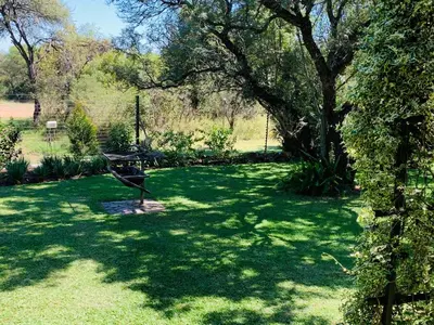 a green yard with a picnic table and a tree at Farm Vibes Guest House in Brits