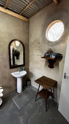 a bathroom with a sink and a mirror and a table at Farm Vibes Guest House in Brits