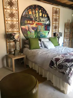 a bedroom with a bed with a large painting on the wall at Farm Vibes Guest House in Brits