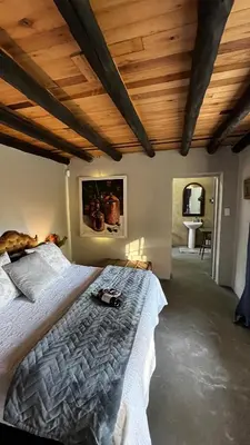 a bedroom with a large bed with a wooden ceiling at Farm Vibes Guest House in Brits
