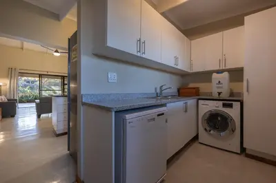 a kitchen with a sink and a washing machine at Lodge 54 in Hoedspruit