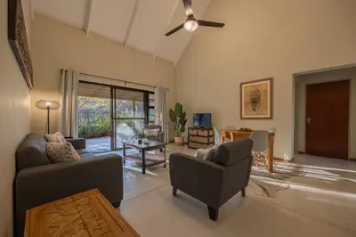 a living room with two couches and a ceiling fan at Lodge 54 in Hoedspruit