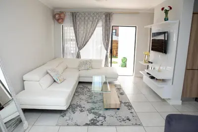 a living room with a white couch and a glass table at The Blyde Riverwalk Estate, Crystal Lagoon, Pretoria east in Pretoria