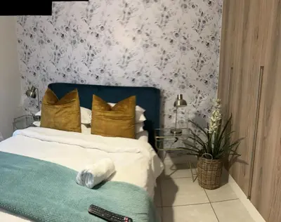 a bedroom with a bed with gold pillows and flowers at The Blyde Riverwalk Estate, Crystal Lagoon, Pretoria east in Pretoria