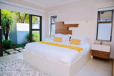 a white bedroom with a large bed and windows at Dam View HOUSE in Hartbeespoort